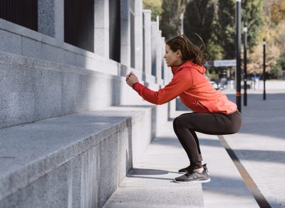 fitness woman doing jump squats outdoors on steps, compound exercises to melt belly fat