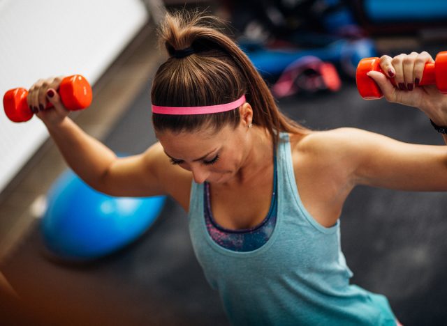 woman lifting dumbbells at the gym, concept of performing drop set
