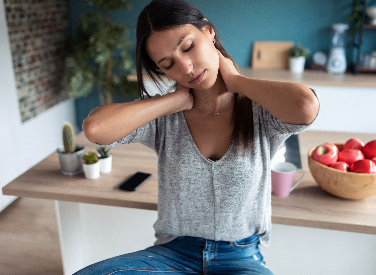 woman doing neck stretches for a stiff neck in her kitchen