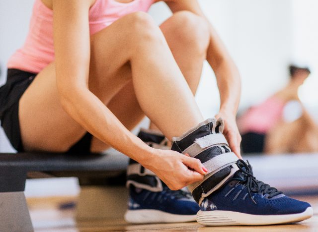 woman putting on ankle weights for ankle weight exercises at the gym