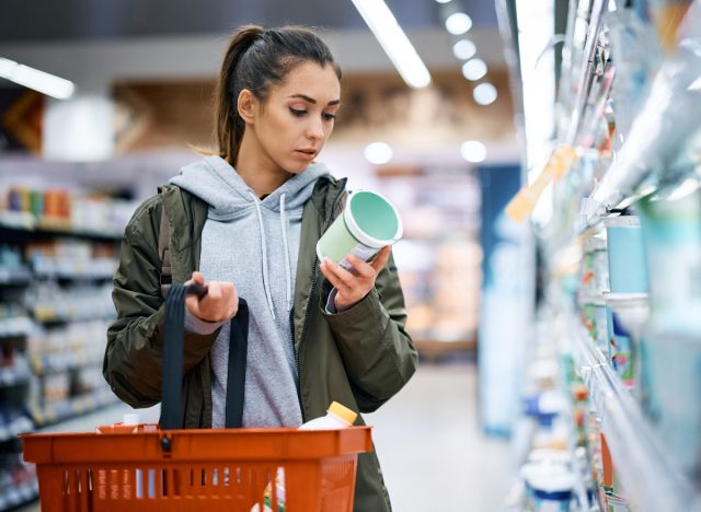 woman reading a food label while grocery shopping