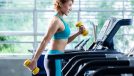 fitness woman doing incline cardio workout on treadmill holding dumbbells
