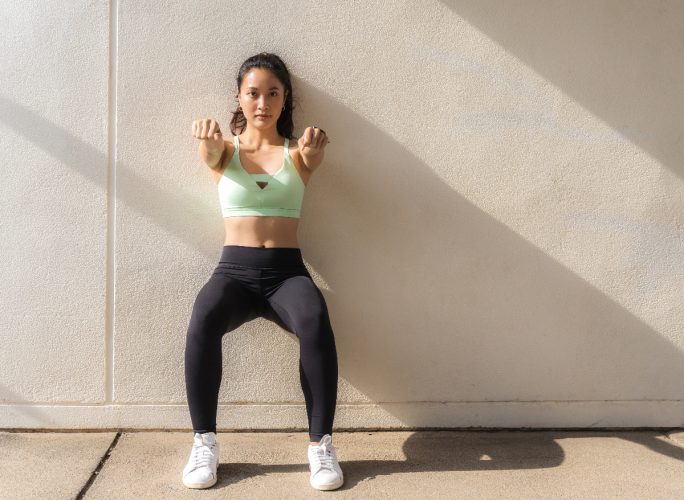 woman doing wall sits, slides exercise as part of low-intensity workout for weight loss