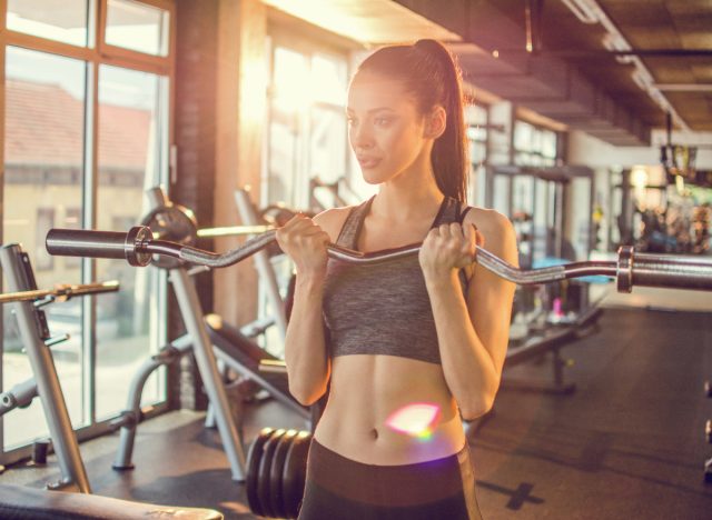 woman demonstrating EZ bar curls to tone your arms in 30 days