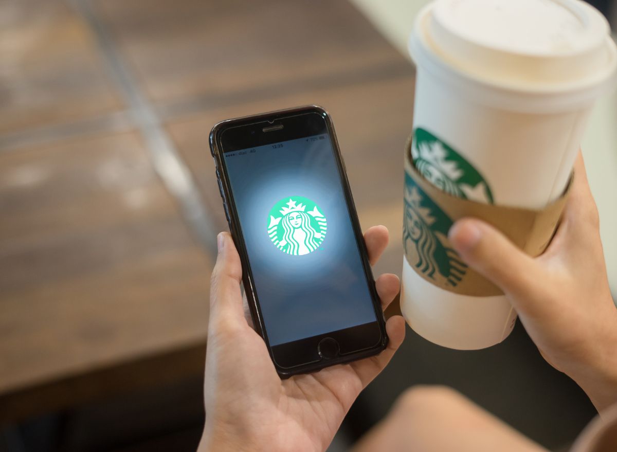 Starbucks logo on phone, with customer holding Starbucks cup