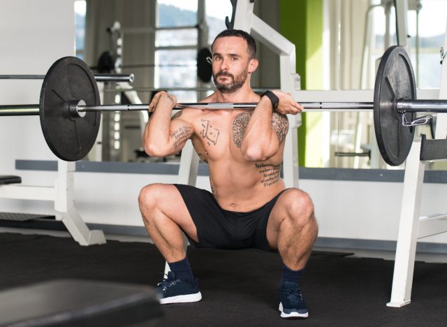 man doing barbell front squats at the gym