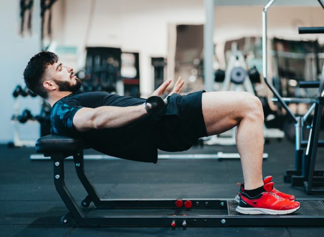 muscular man doing barbell hip thrusts at the gym, concept of butt-toning exercises for men