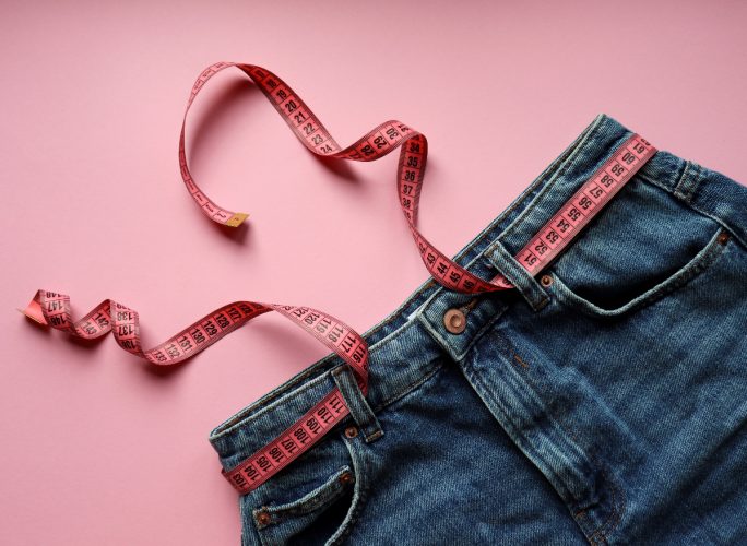 tape measure around jeans, concept of tips for women to lose belly fat
