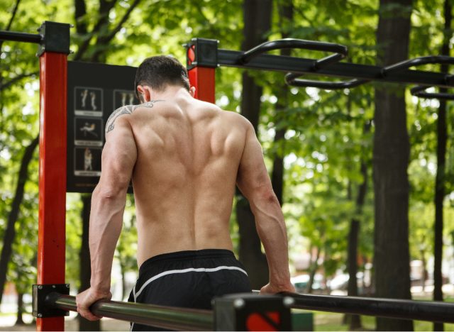 muscular man doing bodyweight dips to build broader shoulders