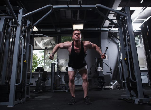 man doing cable flies exercises to build broader shoulders at the gym