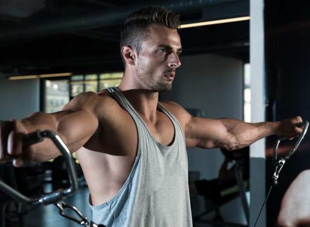 muscular man doing cable machine lateral raise exercise