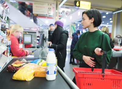 Standing at the supermarket checkout and waiting to pay.