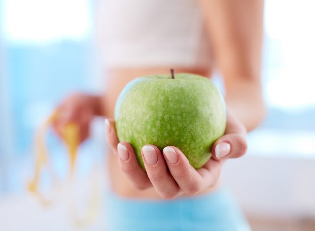 close-up of woman's hand holding green apple