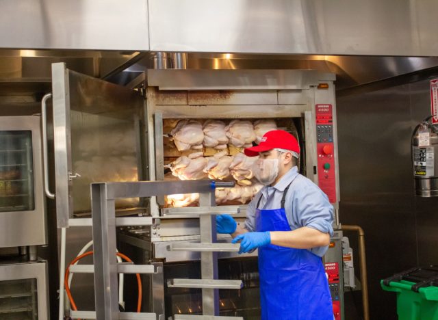 costco worker preparing rotisserie chickens