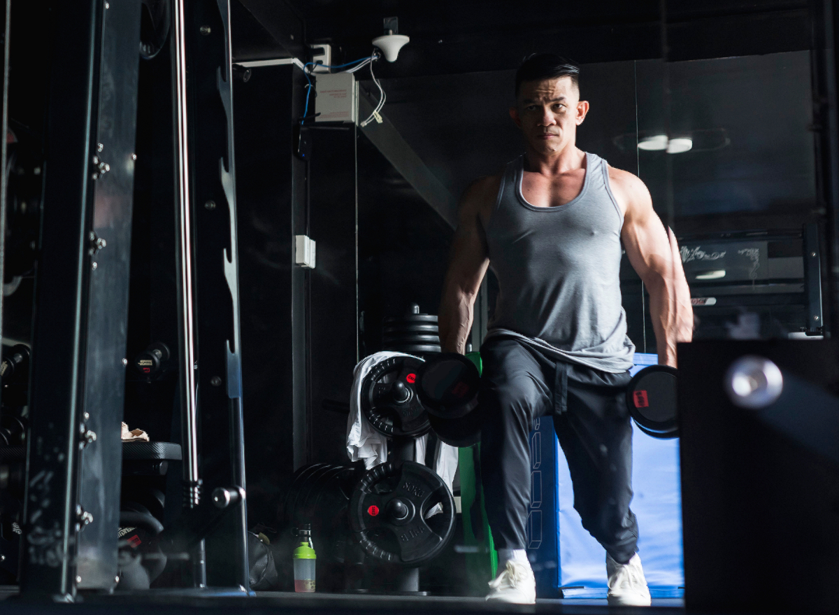 fit man doing dumbbell lunges, leg-strengthening exercises at the gym