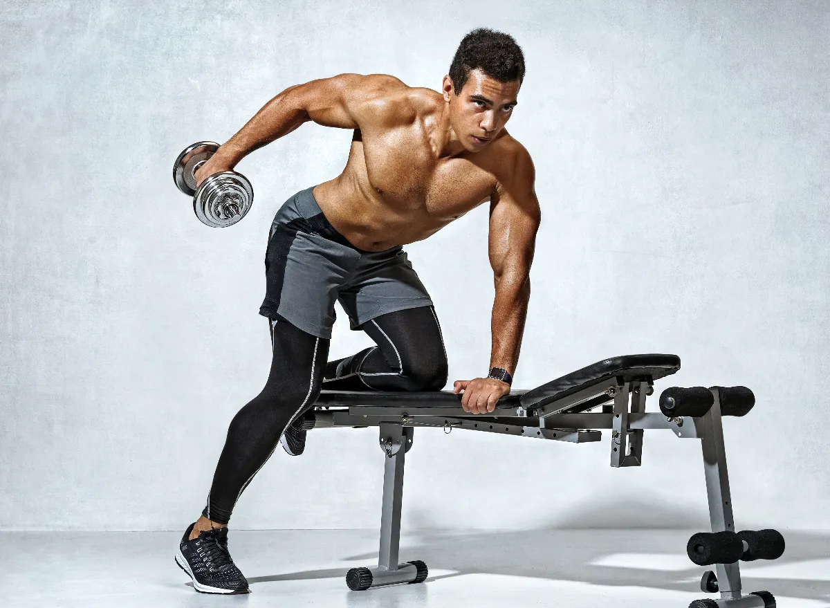 muscular man exercising on workout bench, concept of dumbbell exercises for bigger triceps