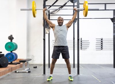 fit man doing barbell overhead press during muscle-building workout
