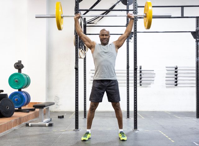 fit man doing barbell overhead press as part of hypertrophy workout to build size and strength