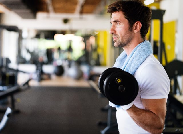 fit man doing bicep curls at the gym, close-up, concept of mistakes men make at the gym that hurt progress