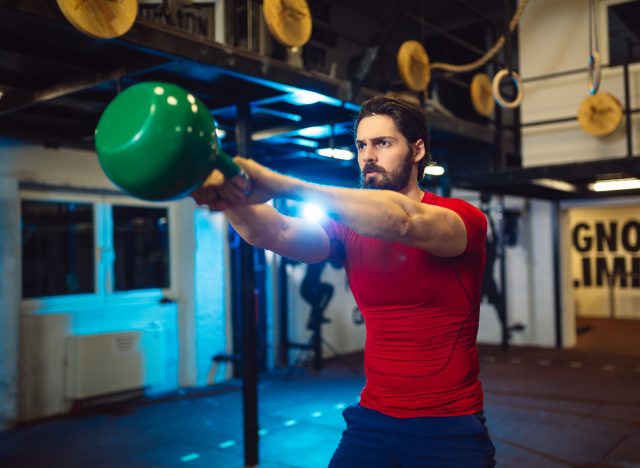 vältränad man gör kettlebell-gungor på gymmet, begreppet misstag med kettlebells