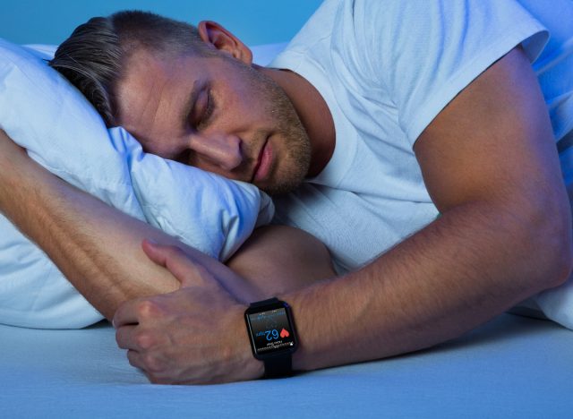 passar medelålders man sover, bär fitness sömn tracker