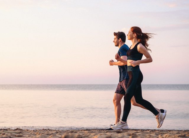 fitness couple running on the beach