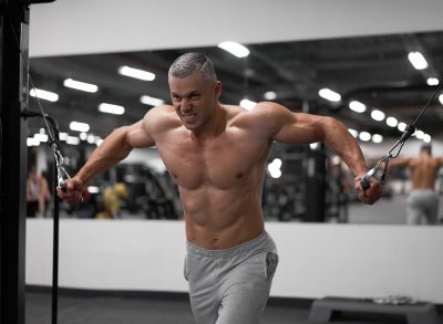 muscular man doing cable machine workout for bigger pecs