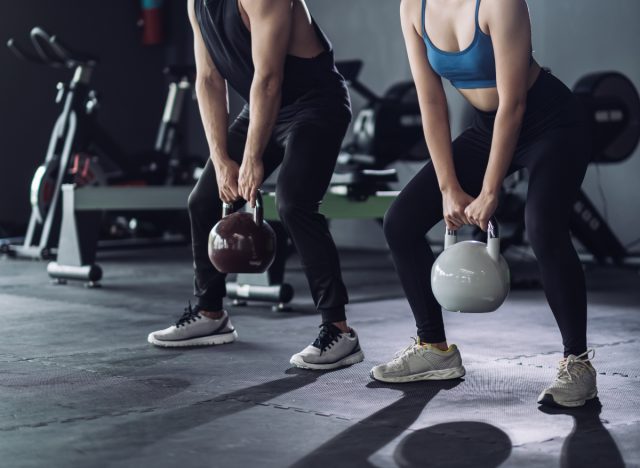 two people doing kettlebell deadlift at the gym