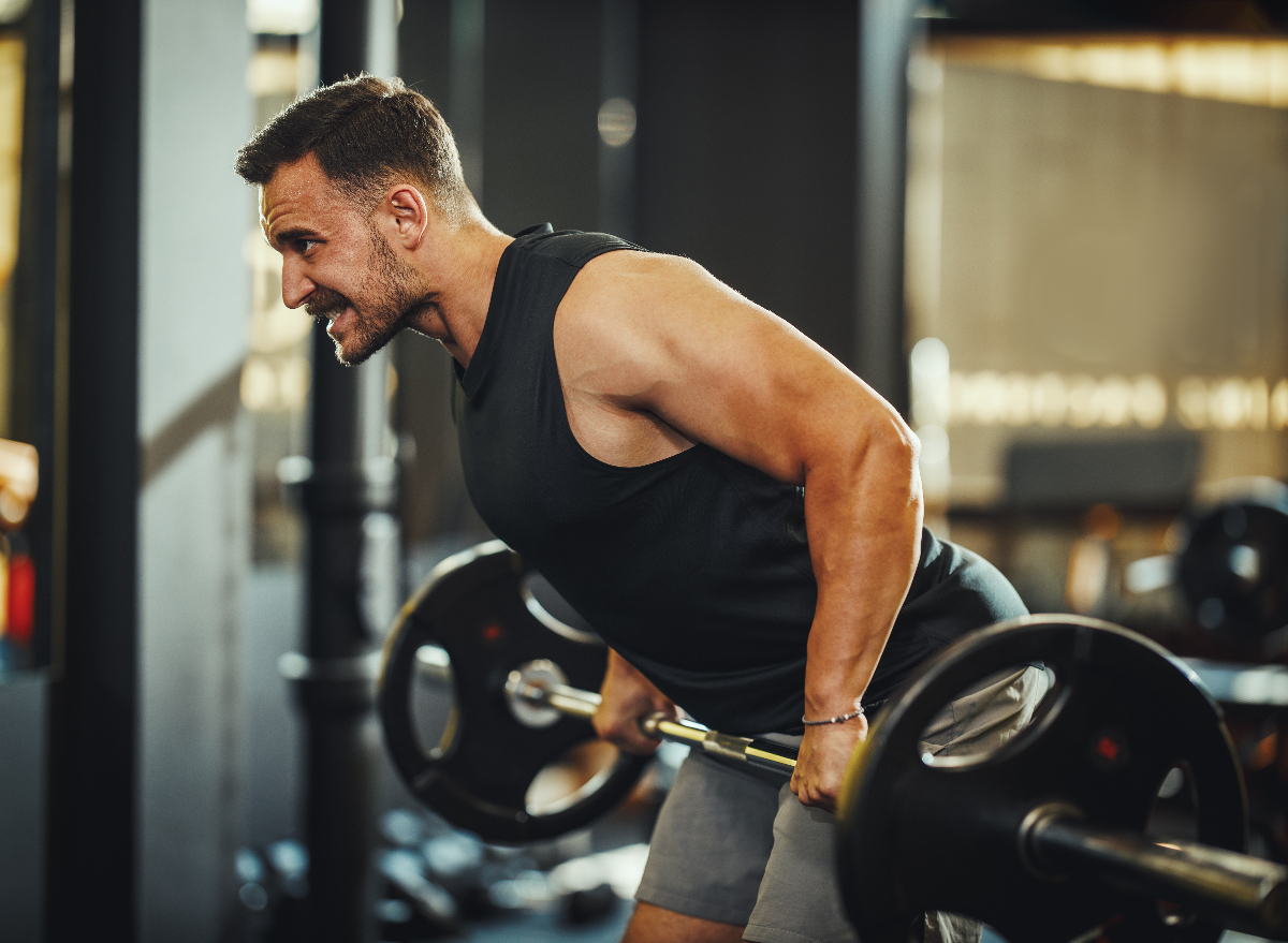 fit muscular man doing barbell exercises to increase testosterone