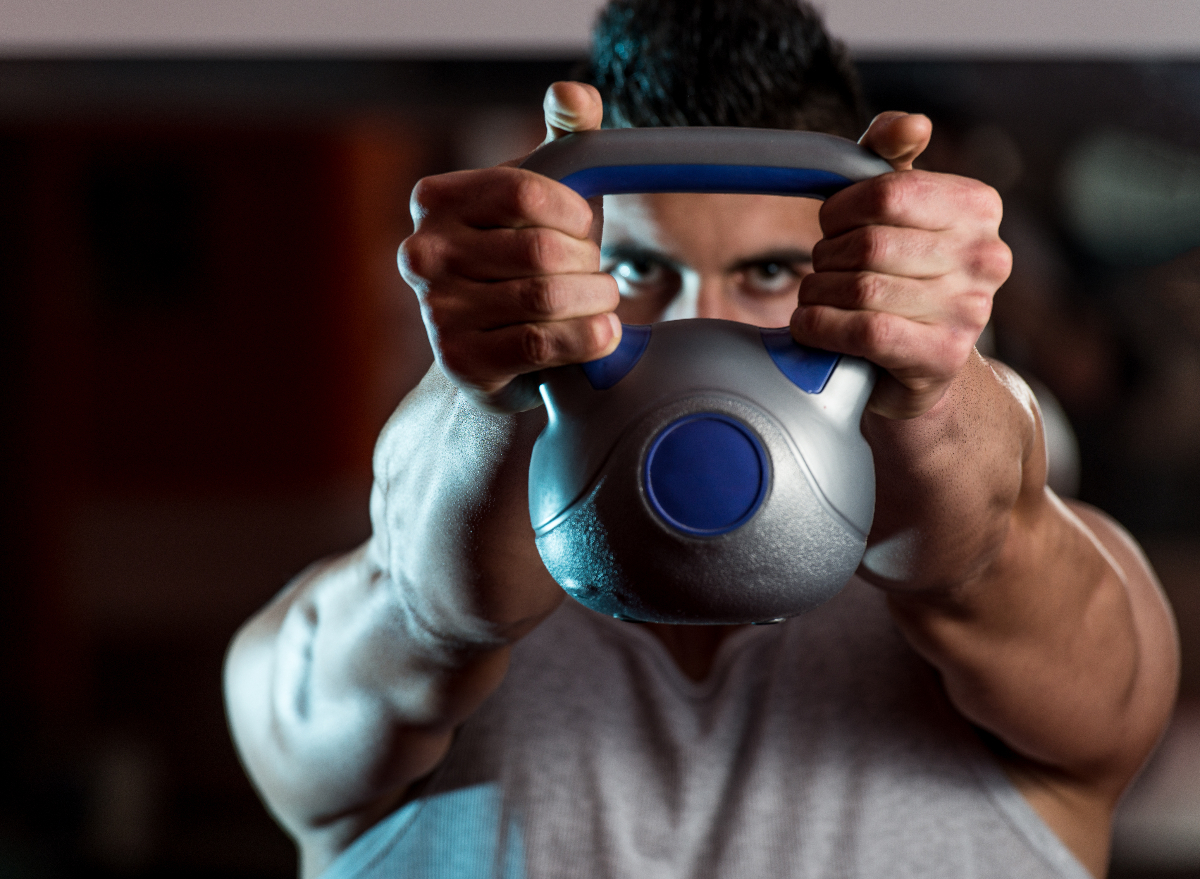 fit man holding kettlebell, demonstrating exercises for men to get bigger arms