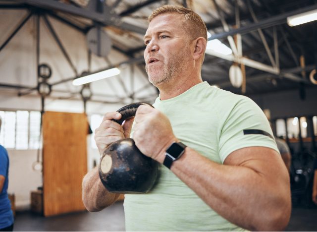 man lifting kettlebell, demonstrating free weights exercises to get rid of a dad belly