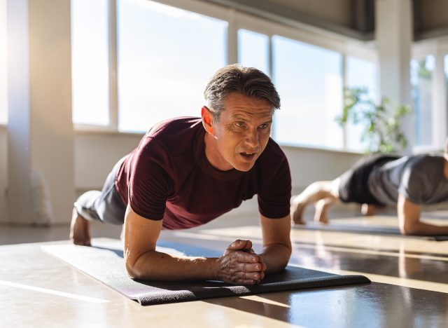 mature man doing planks during group fitness class, concept of exercises for men to build strength