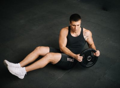 man doing russian twists with weight plate to get rid of hanging belly fat