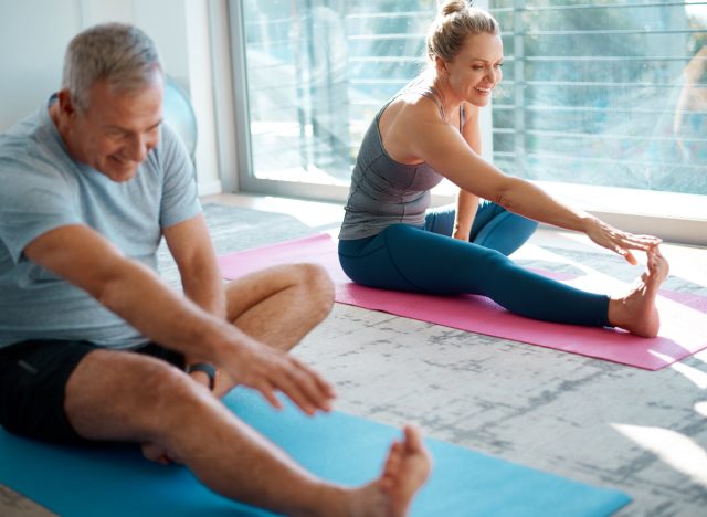 mature couple stretching at home on yoga mats