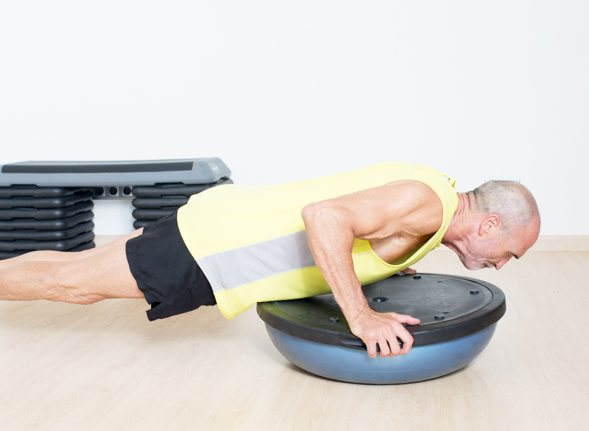 mature man doing balance training workout planks on a BOSU ball