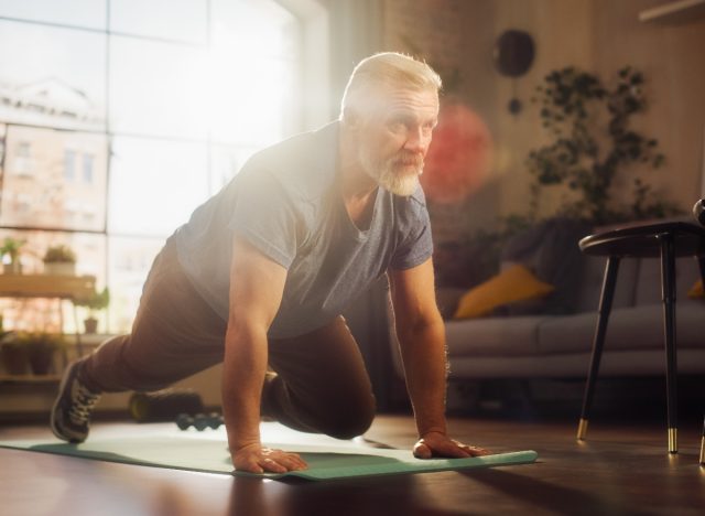 mature man doing mountain climbers at home on yoga mat