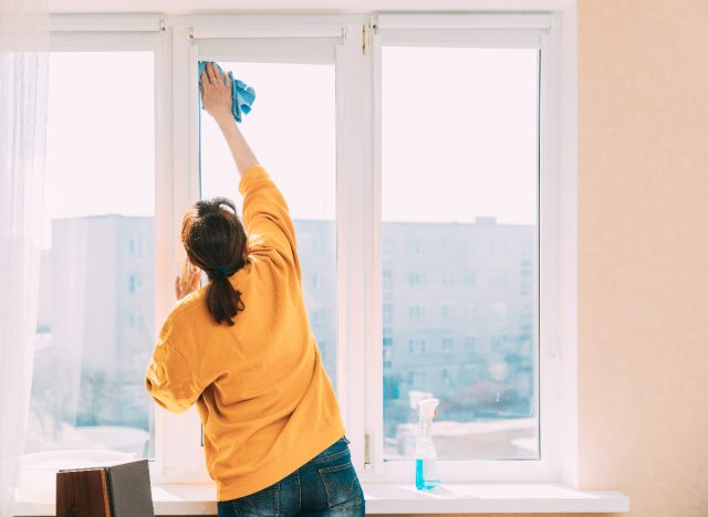 mature woman cleaning her windows at home, house chores