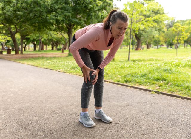Reife Frau, die unter Knieschmerzen leidet, während sie Cardio durchführt, beim Laufen