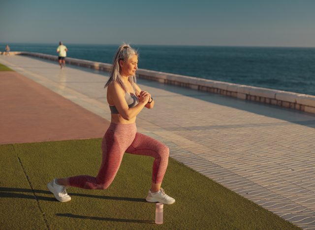 mature woman doing lunges outdoors by the water, bodyweight exercises to slow aging concept