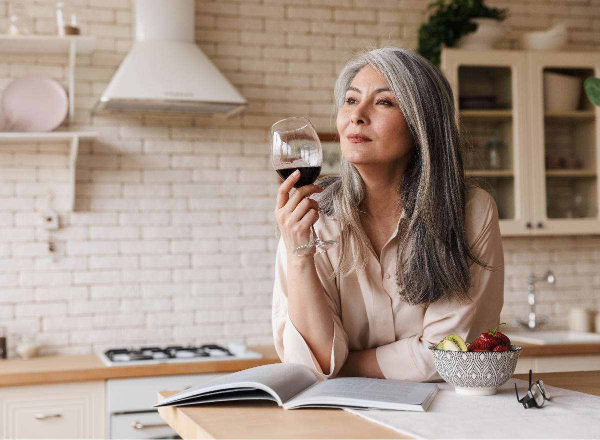 middle-aged woman drinking red wine alone at home, concept of health mistakes after 50