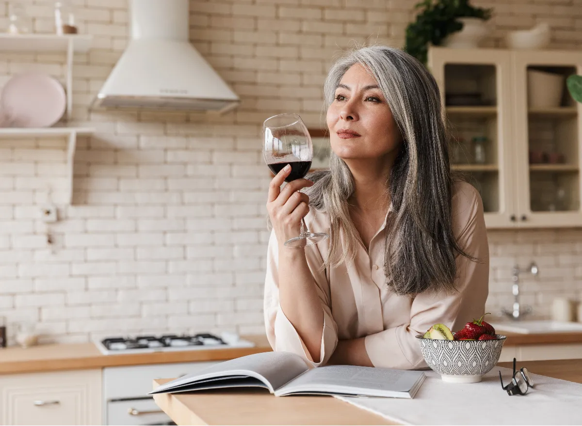 middle-aged woman drinking red wine alone at home, concept of health mistakes after 50