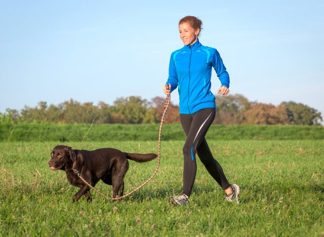 medelålders kvinna springer utomhus med sin hund