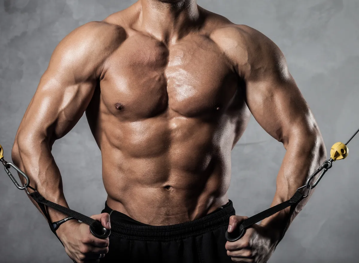 muscular man holding cables demonstrating exercises to build broader shoulders