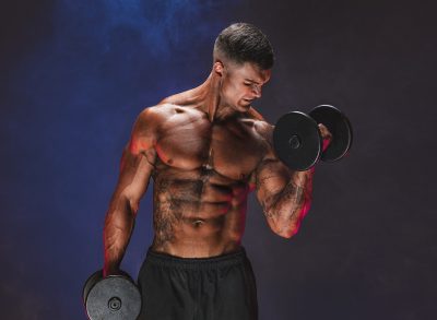 muscular man lifting weights doing dumbbell exercises