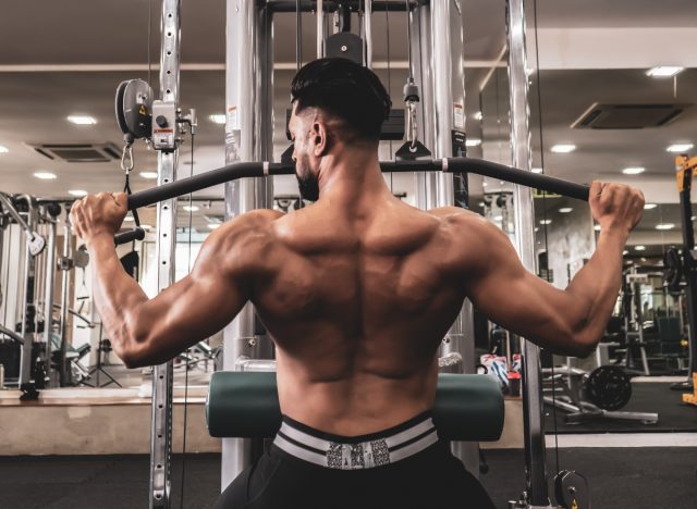 muscular man doing lat pulldowns at the gym, part of workout for V-taper back