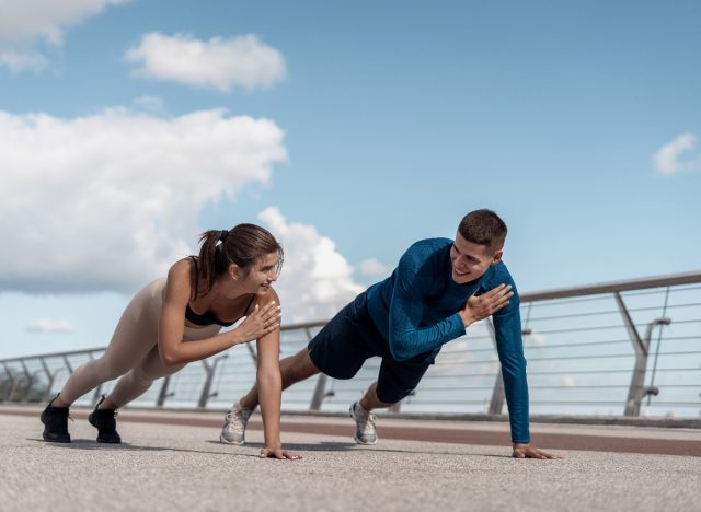 couple doing planks with shoulder taps during outdoor workout