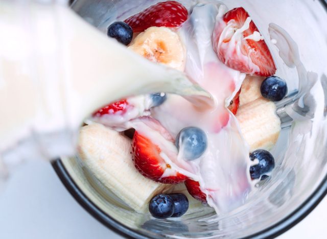 pour milk into a berry smoothie in blender