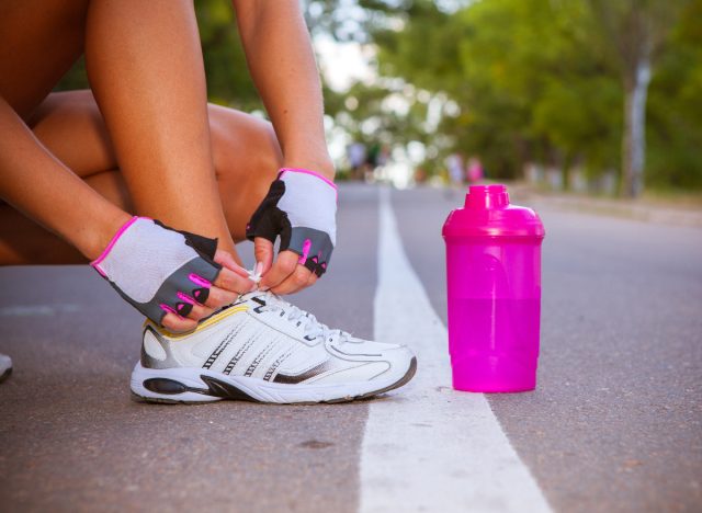 close-up female runner tying sneakers on paved road