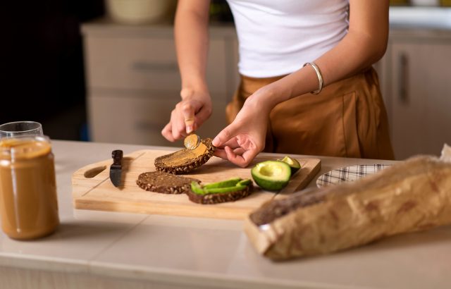 woman making peanut butter and avocado toast
