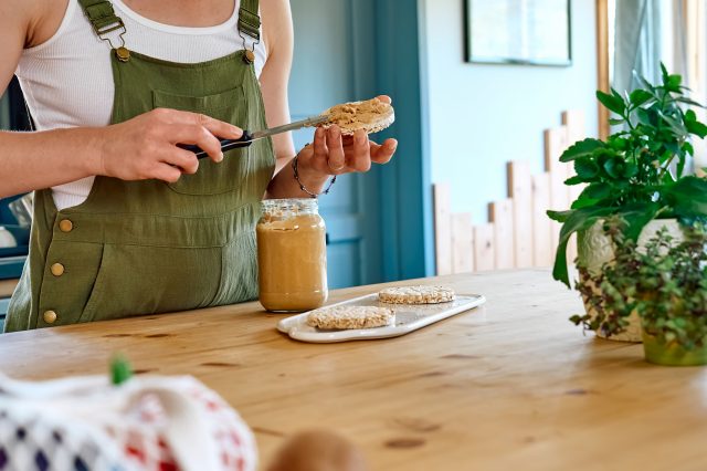 woman making a healthy peanut butter rice cakes breakfast